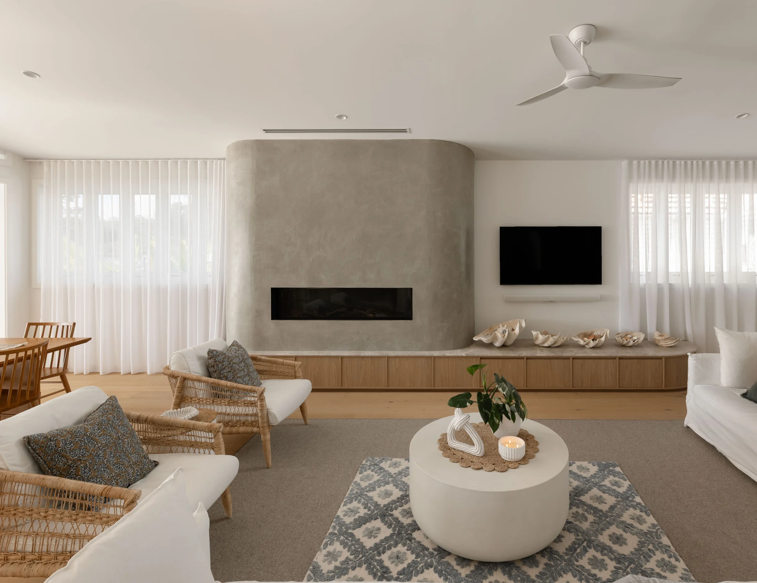 Curved microcement feature wall wrapping a linear fireplace in a Fairfield living room, hand-applied by Dune Artisan Finishes Co. in Brisbane.